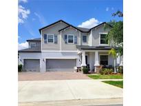 A beautiful two-story home featuring a three-car garage and well-manicured landscaping under a bright, partly cloudy sky at 11704 Navajo Sandstone St, Riverview, FL 33579