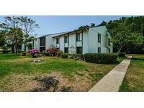 Charming two-story condo with lush landscaping and colorful flowers along the walkway at 1290 Pine Ridge E Cir # G1, Tarpon Springs, FL 34688
