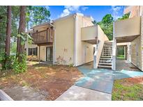 Two-story condo with yellow siding, a small patio and a stairway to an upper unit at 134 Sycamore Ln # F, Oldsmar, FL 34677