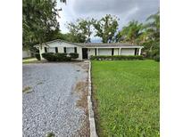 Charming single-story home featuring a well-maintained lawn, a rock driveway, and manicured shrubbery at 1412 Sunset Ln, Lutz, FL 33549