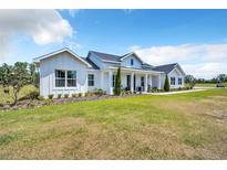 Beautifully landscaped lawn featuring a modern farmhouse with clean lines and manicured shrubbery at 14902 Sweat Loop Rd, Wimauma, FL 33598