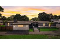 Charming single-story home with a well-manicured lawn and driveway at sunset at 2679 Haines Bayshore Rd, Clearwater, FL 33760