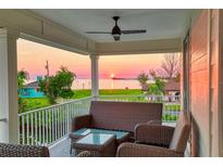 Inviting covered porch with wicker furniture to enjoy sunset and waterfront views at 3174 Sanibel Dr, Hernando Beach, FL 34607