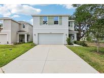 Two-story home featuring a two-car garage, tidy lawn, and charming green shutters at 36557 Night Strawberry Ct, Dade City, FL 33525