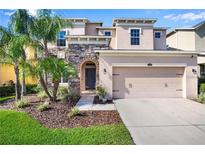 Charming two-story home featuring stone accents, a two-car garage, and lush landscaping at 4407 Scarlet Loop, Wesley Chapel, FL 33544
