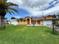 Inviting one-story home featuring bright yellow siding, red roof, arched entrance, and a lush green lawn at 4593 Goldcoast Ave, Spring Hill, FL 34609