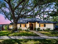 Inviting single-story home boasts lush landscaping, beautiful trees, and a charming entrance at 5021 Roanoke Dr, Holiday, FL 34690