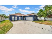 Charming single-story home with a blue exterior, arched windows, and a spacious driveway at 650 Arbor Ln, Largo, FL 33770