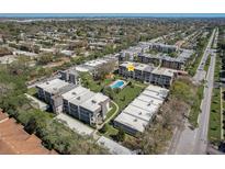 Aerial view of condo buildings with a community pool and well-maintained green spaces, and a road nearby at 8703 Bardmoor Blvd # 305, Seminole, FL 33777