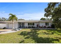 Charming single-story home featuring a well-manicured lawn, palm tree and inviting entryway with stylish Adirondack chairs at 1039 Union St, Clearwater, FL 33755