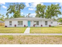 Charming one-story home features a vibrant turquoise door and a well-maintained lawn with manicured landscaping at 2901 Forestwood Dr, Seffner, FL 33584