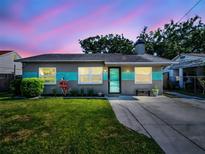 Charming single-story home features a well-maintained lawn, updated gray facade and a welcoming front entrance at 37 W Boyer St, Tarpon Springs, FL 34689