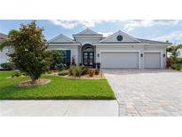 Beautiful single-story home with a three-car garage, paver driveway, manicured lawn, and mature trees at 3727 Wild Blossom Pl, Parrish, FL 34219