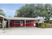 Charming single-story red house with a covered parking area and an American flag at 3940 E Knights Griffin Rd, Plant City, FL 33565