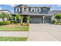 Two-story home featuring a three-car garage, stone accents, well-manicured landscaping, and decorative shutters at 4094 Windcrest Dr, Wesley Chapel, FL 33544