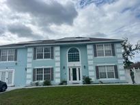 Two-story light blue home with white trim, brown shutters, solar panels, and well-maintained lawn at 5391 Baldock Ave, Spring Hill, FL 34608