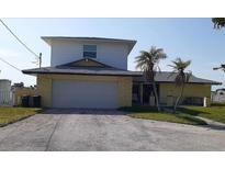 Two-story home featuring an attached two-car garage, palm trees, and a well-maintained front yard at 5930 Bahama N Way, St Pete Beach, FL 33706