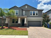 Charming two-story home with neutral gray siding, brick-paved driveway, and a well-manicured lawn at 6244 English Hollow Rd, Tampa, FL 33647