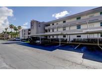 Exterior view of the building with covered parking and well-maintained landscaping at 7425 Bay Island S Dr # 203, South Pasadena, FL 33707