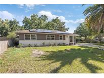 Charming single-story home featuring solar panels, a well-maintained lawn, and lovely mature trees at 1341 Sandy Ln, Clearwater, FL 33755