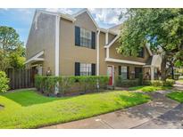 Inviting home with lush green lawn, mature trees, black shutters, and a charming red front door at 16504 Lake Brigadoon Cir, Tampa, FL 33618