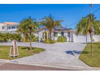 Charming single-story home with a well-manicured lawn, palm trees, and a paved driveway leading to an attached garage at 300 10Th Ave, Indian Rocks Beach, FL 33785