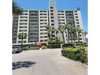 Exterior of the condo building with parking and palm trees in a desirable location at 7150 Sunset Way # 405, St Pete Beach, FL 33706