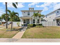 Charming two-story home with manicured lawn and walkway leading to the front door surrounded by palms and white fencing at 785 52Nd N Ave, St Petersburg, FL 33703