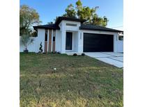 Modern home featuring black garage door, stylish white facade, and freshly cut lawn at 907 E Okaloosa Ave, Tampa, FL 33604