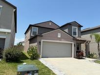 Two-story home showcasing neutral color palette, well maintained lawn, and a two car garage at 9616 Lemon Drop Loop, Sun City Center, FL 33573