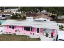 Single story home, painted pink, with white trim, landscaping, and grey roof in a quiet neighborhood at 12425 Ridge Rd, Largo, FL 33778