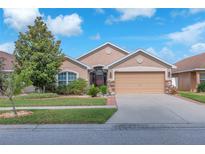 Charming single-story home with well-maintained landscaping and a two-car garage under a sunny sky at 14233 Edinburgh Moor Dr, Wimauma, FL 33598
