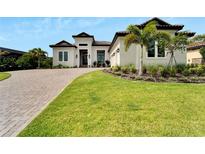 Stunning home features a lush lawn, beautiful landscaping and a brick driveway at 14911 Tavares Mill Ave, Lithia, FL 33547