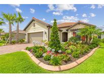 Charming home featuring a well-manicured lawn, colorful flower bed, and lush tropical landscaping at 4165 San Severo Rd, Wesley Chapel, FL 33543