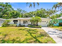 Charming single-story home featuring lush landscaping, mature trees, and a well-maintained front lawn at 417 Broadway, Dunedin, FL 34698