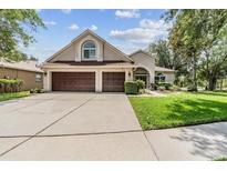 Charming single-Gathering home featuring a two-car garage, well-maintained lawn, and mature trees at 6038 Palomaglade Dr, Lithia, FL 33547