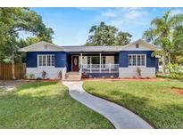 Charming blue two-story home featuring a welcoming front porch and well-maintained lawn at 6110 N Suwanee Ave, Tampa, FL 33604