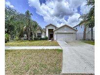 Well-maintained home featuring a two-car garage and lush landscaping in a residential neighborhood at 7504 Turtle View Dr, Ruskin, FL 33573
