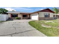 Charming single-story home with a brick and siding exterior, attached garage, and curved driveway at 811 Pebblewood Dr, Brandon, FL 33511