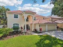 Inviting two-story home with a tile roof, lush landscaping, and a spacious three-car garage at 9203 Meadow Lane Ct, Tampa, FL 33647