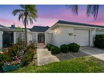 Charming home featuring a well-maintained front yard and decorative privacy wall under a colorful dusk sky at 93 Boca Ciega Point N Blvd # 93, St Petersburg, FL 33708