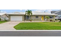 Charming single-story home with a well-manicured lawn, white roof, and a bright yellow front door at 113 16Th St, Belleair Beach, FL 33786