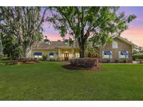 Beautiful two-story home featuring a manicured lawn and mature trees providing shade at 2769 St Andrews Blvd, Tarpon Springs, FL 34688