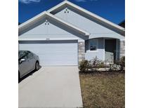 Charming single-story home with a two-car garage and stone accents under a blue sky at 2880 Gumbo Limbo Dr, Wimauma, FL 33598