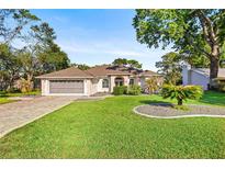 Charming home featuring a lush green lawn, complemented by mature trees and a two-car garage at 5296 Slater Rd, Spring Hill, FL 34608