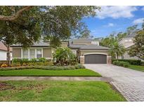 Beautiful home with lush landscaping, brick driveway, and a well-maintained front yard at 14851 Tudor Chase Dr, Tampa, FL 33626