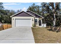 Charming home features a two-car garage, a well-maintained lawn, and a welcoming entrance, all set beneath mature shade trees at 16519 Us Highway 41, Spring Hill, FL 34610