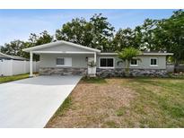 Charming single-story home with a well-manicured lawn, gray paint and stone accents at 3106 Ash Ct, Dunedin, FL 34698