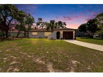 A warm sunset complements this cozy home, featuring an arched entry and manicured landscaping at 3344 Blythe Ave, Spring Hill, FL 34609