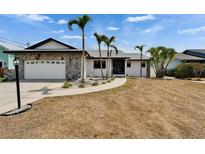 A quaint, single-story home with an attached garage, stone facade, and tropical landscaping at 743 Kingston Ct, Apollo Beach, FL 33572